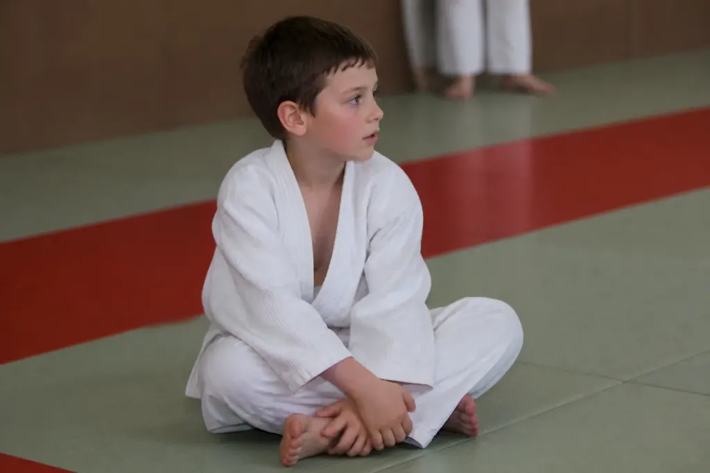 Jeune debutant assis sur tapis genoux legerement flechis